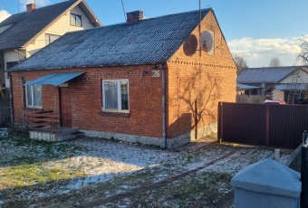 Dom z budynkami gospodarczymi, łąką i stawem.